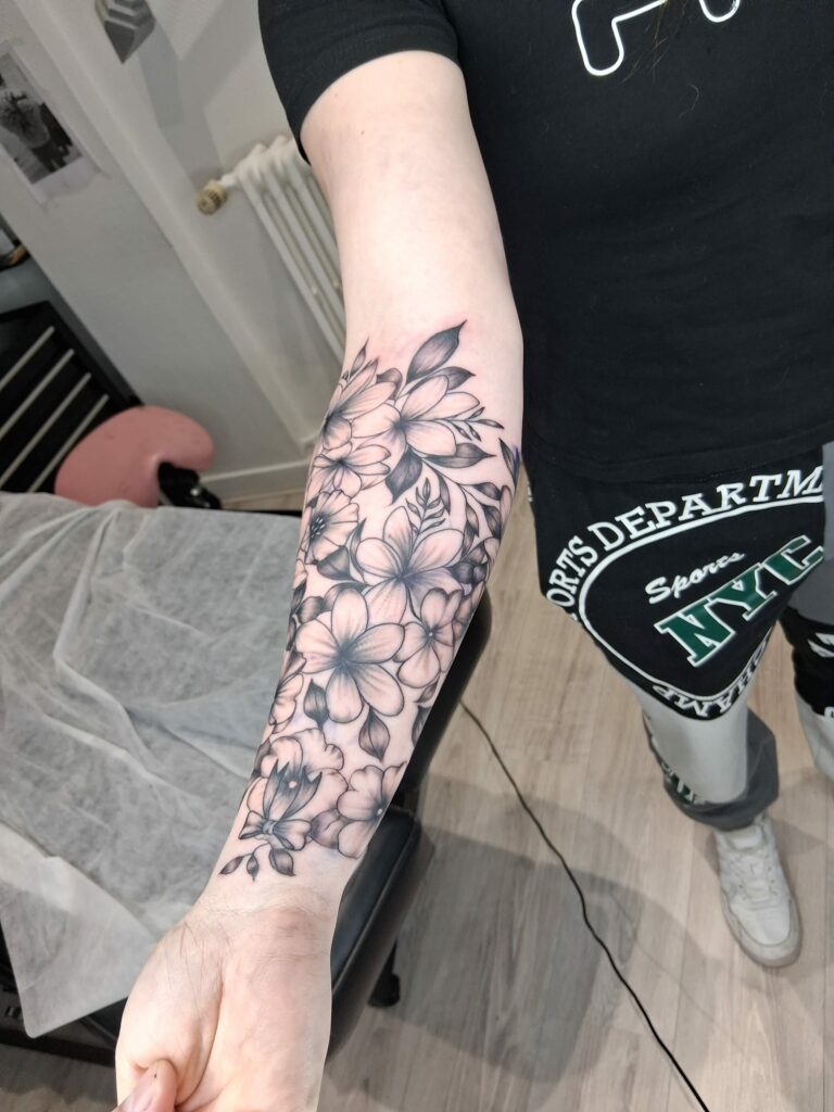 Tatouage floral de fleurs et feuillage sur l'avant-bras à Troyes