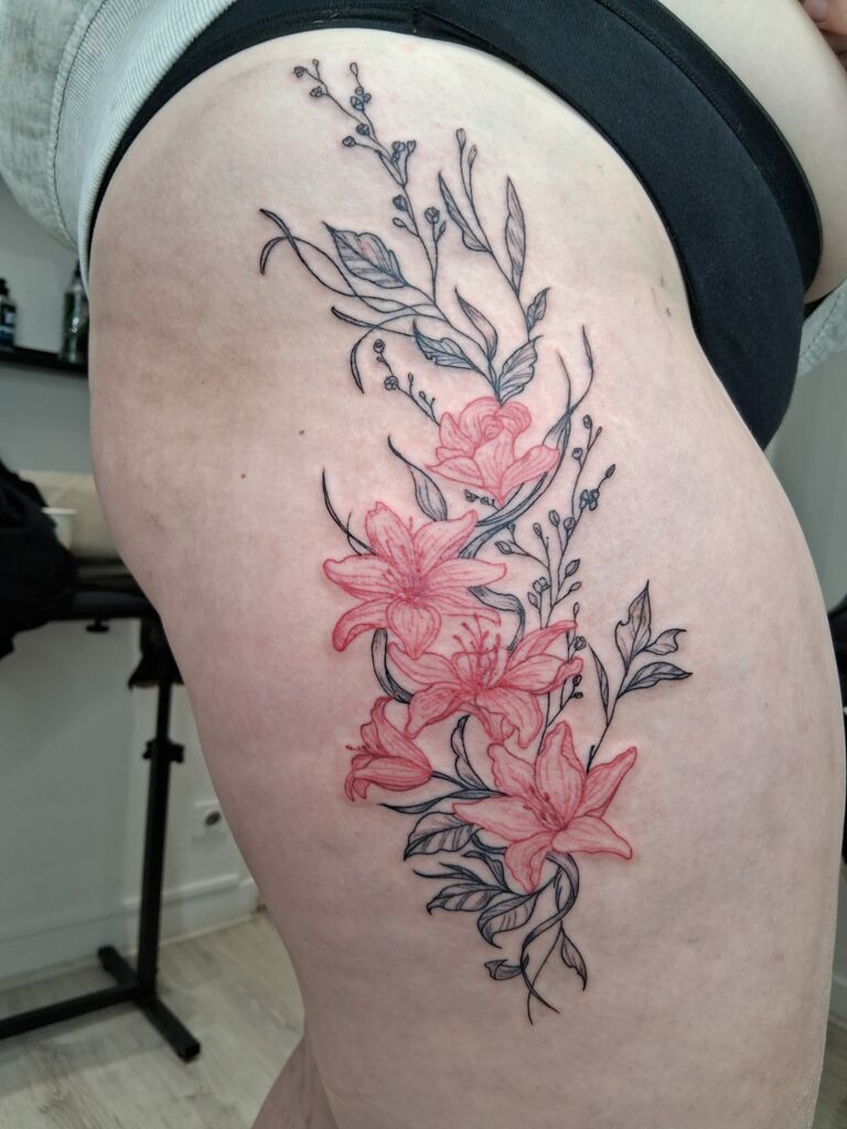 Tatouage de fleurs roses et feuillage sur la cuisse à Troyes